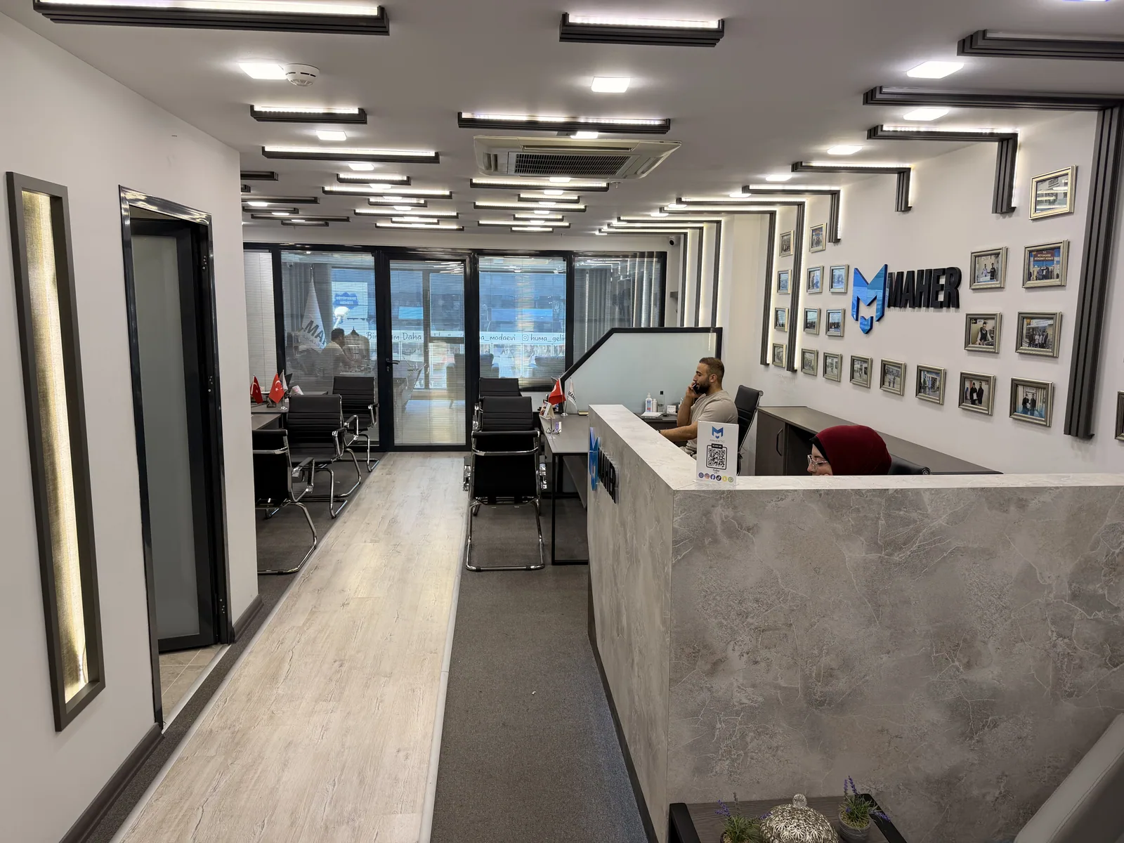 The reception desk, with the Maher logo and the wall of framed photographs behind it